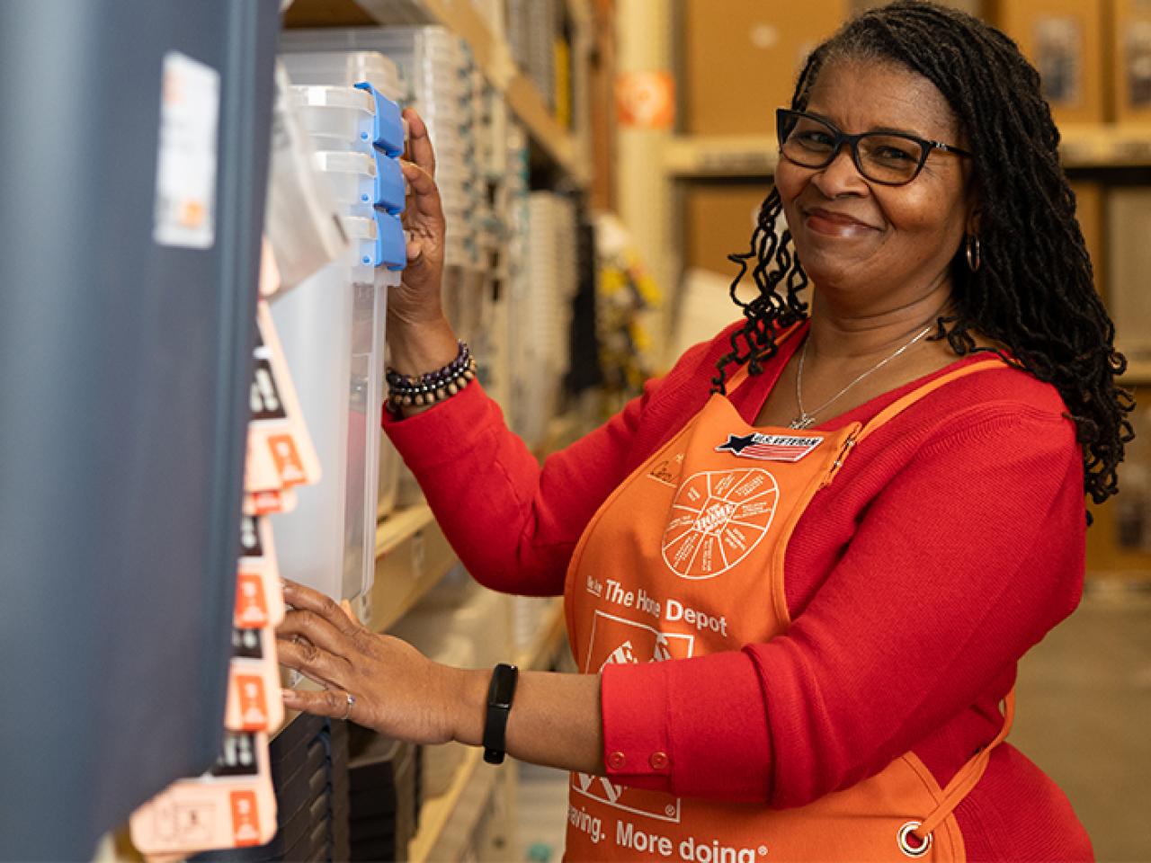 Home Depot associate shown in her store working on restocking a shelf.